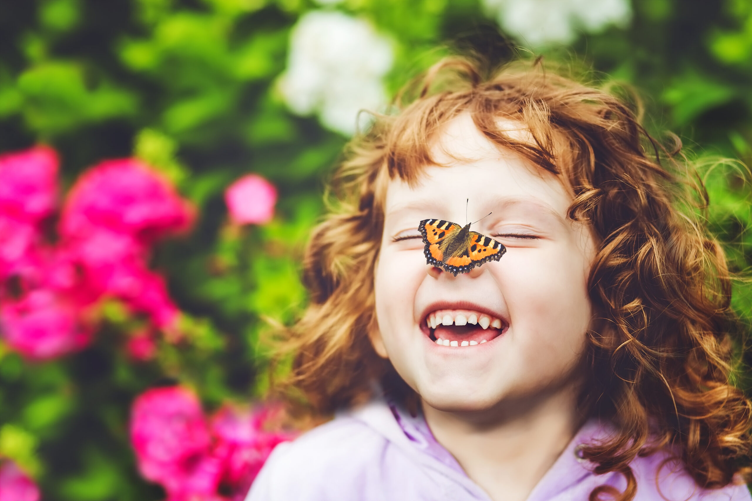 Laughing child with a butterfly on their nose.